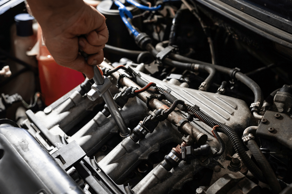 Close-up of a technician using a wrench on engine components during automotive engine repair service.